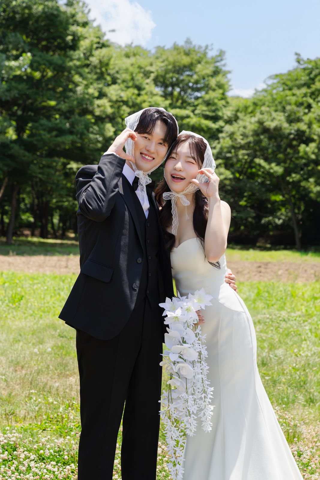 들판에서 흰 손수건을 머리에 쓰고 웃는 두 사람