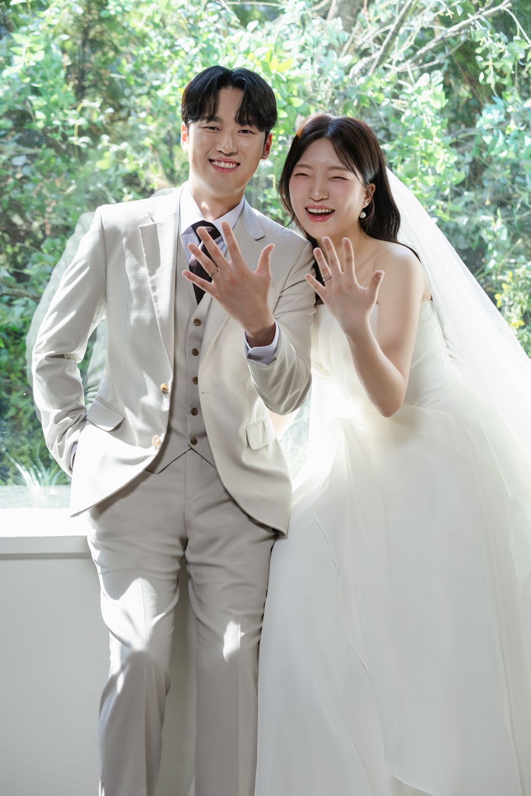 창가에서 반지 낀 손을 보여 주며 웃는 두 사람